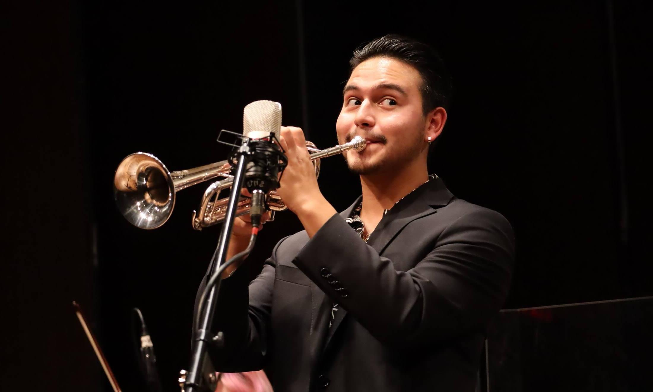 A man playing the trumpet on stage in front of a microphone.